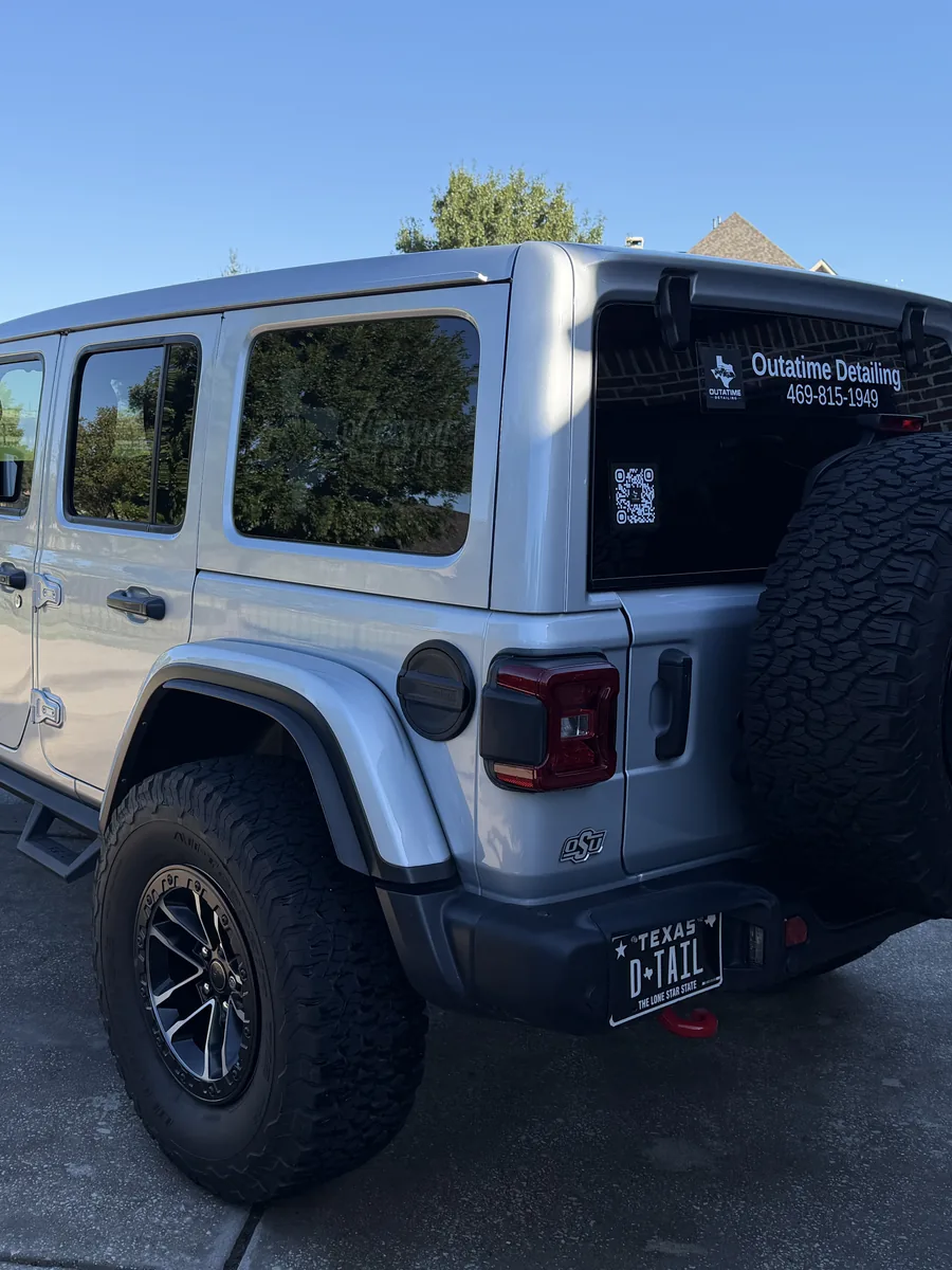 The OutaTime Detailing Jeep, rear three-quarter view in evening light, company name and phone number on the rear window