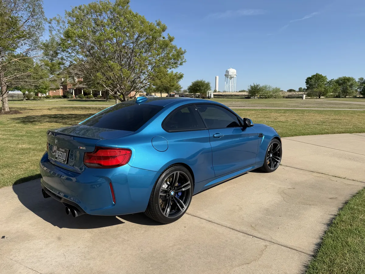 Blue BMW coupe, rear three-quarter view on a driveway