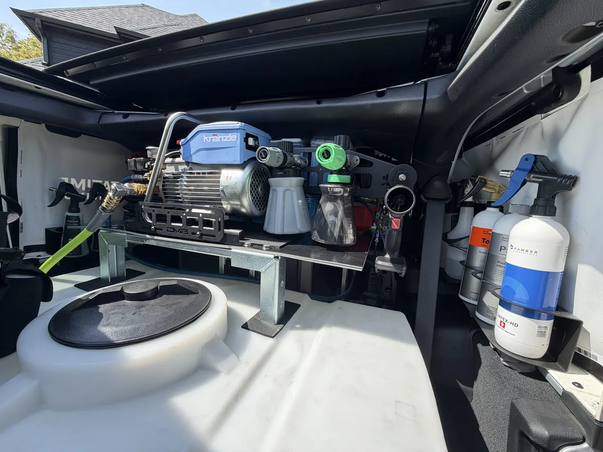 Inside the Jeep: pressure washer mounted above the water tank, with chemical bottles in fitted holders