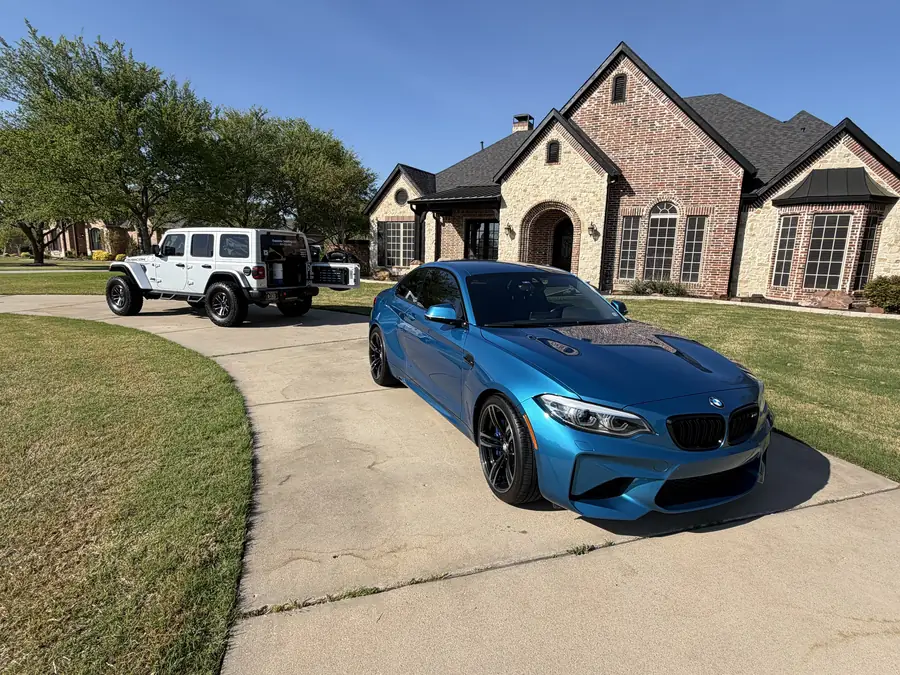 Blue BMW coupe on a client's driveway with the OutaTime Jeep in the background