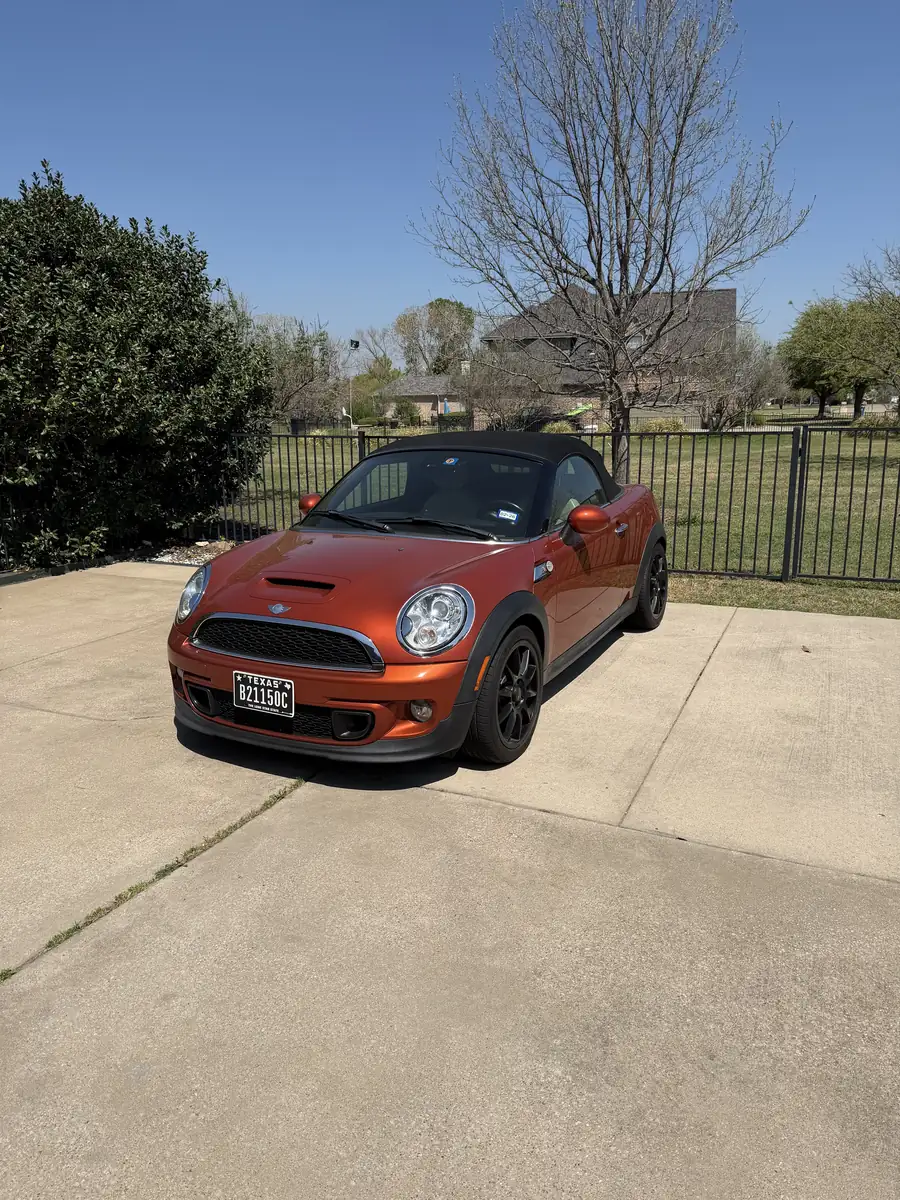 Orange MINI convertible with a black soft top on a driveway